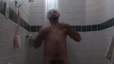 Um cara com grandes pelos pubianos tomando banho.